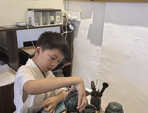 Child experiencing traditional Chinese tea culture at Hong Meng Academy