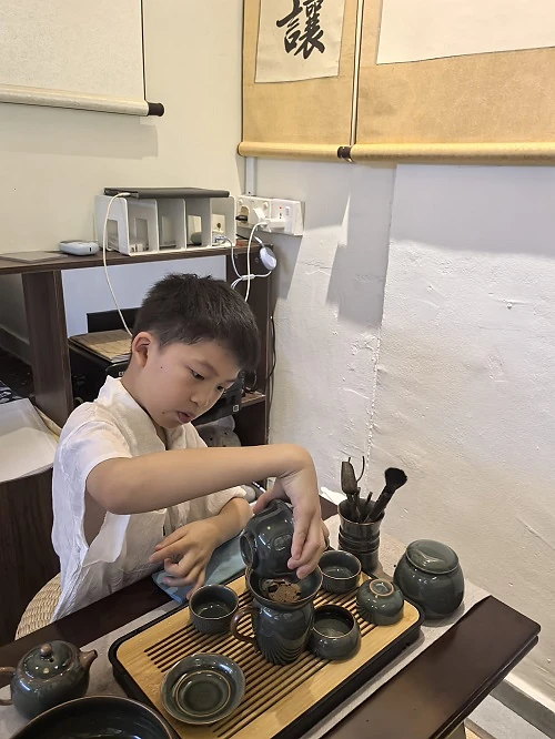 Child experiencing traditional Chinese tea culture at Hong Meng Academy
